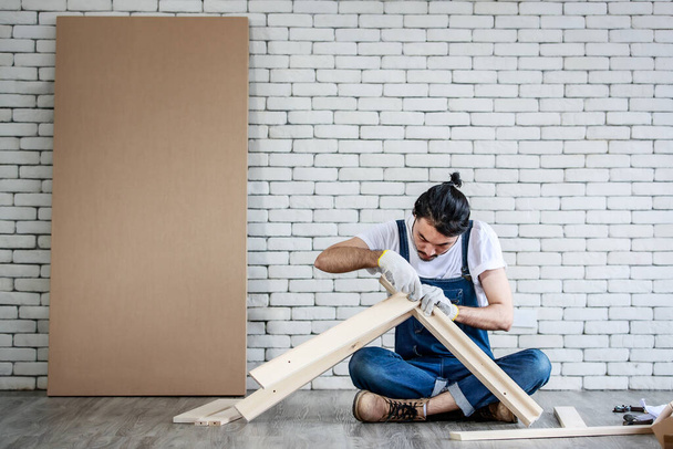 Junger Hipster asiatischer Mann arbeitet als Heimwerker, montiert Holztisch mit Geräten, Konzept für Heimtextilien und Selbstbedienung zu Hause. - Foto, Bild