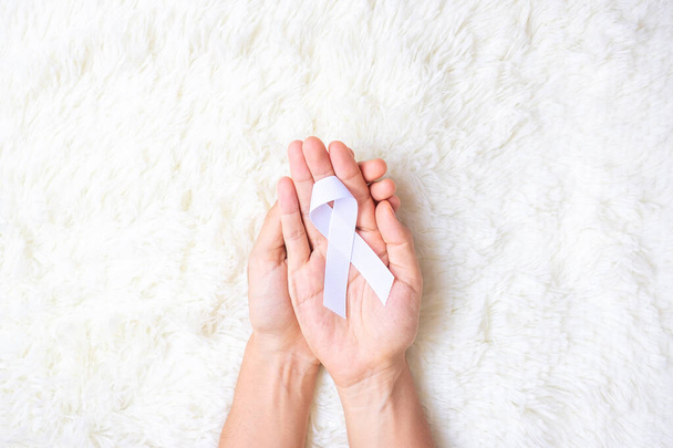 Novembre Mois de sensibilisation au cancer du poumon, démocratie et journée internationale de la paix. Homme tenant un ruban blanc sur fond blanc - Photo, image