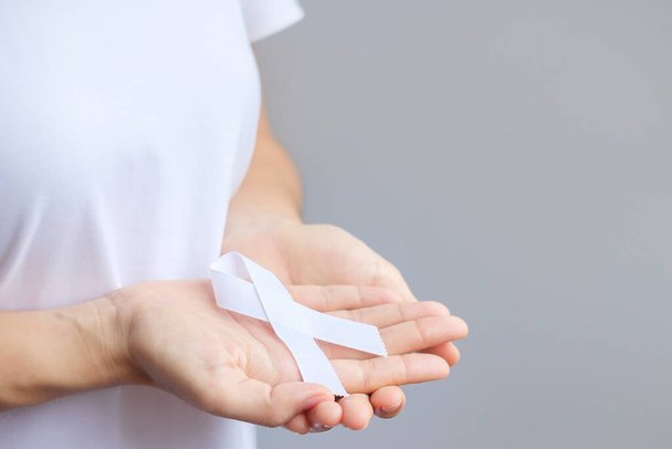 Woman holding white Ribbon for November Lung Cancer Awareness month, democracy and international peace day. Healthcare concept - Photo, Image