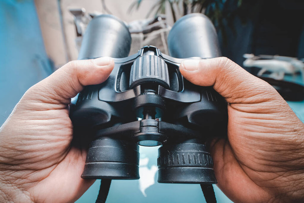 A shallow focus shot of a person holding binoculars - Zdjęcie, obraz