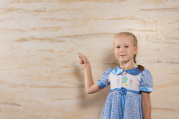 Cute girl pointing to the wooden wall behind her - Fotografie, Obrázek