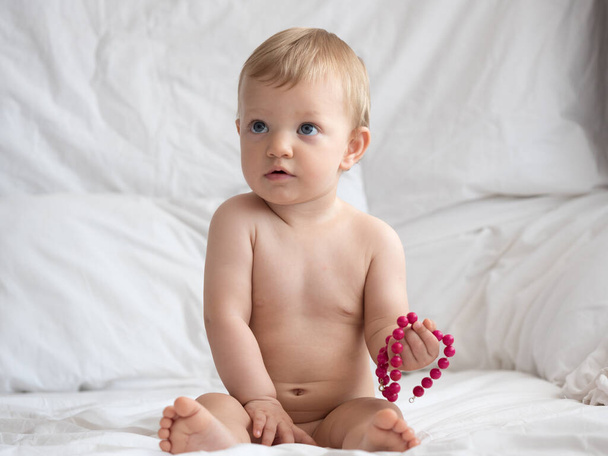 Cute caucasian baby girl with bracelet in bed - Foto, afbeelding