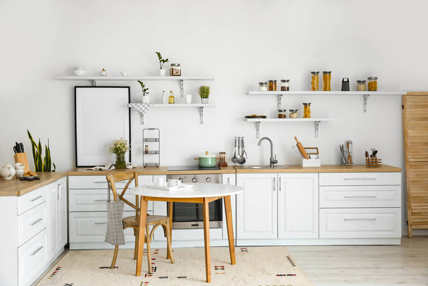 Інтер'єр світлої сучасної кухні з порожньою плакатною рамою і стильними меблями
 - Фото, зображення