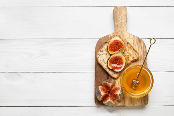 トーストに新鮮な熟したイチジクと蜂蜜の光木製の背景 - 写真・画像