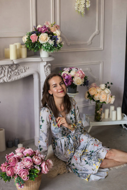 Mulher bonita sentada em um quarto entre as flores - Foto, Imagem