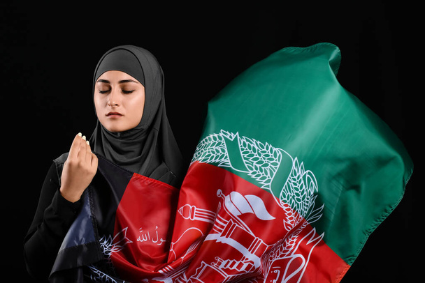 Μουσουλμάνα γυναίκα με σημαία Αφγανιστάν σε σκούρο φόντο - Φωτογραφία, εικόνα