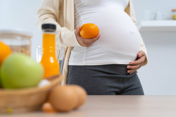 妊娠28週目の女性はオレンジを保持し、彼女の生まれていない子供の健全な発達と成長のための栄養価の高い食事を選択します. - 写真・画像