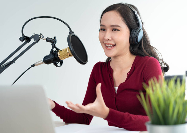 Bright Asian women record a podcast with a microphone and computer camera. A young woman work from home studio.  broadcast studio concept - Foto, imagen