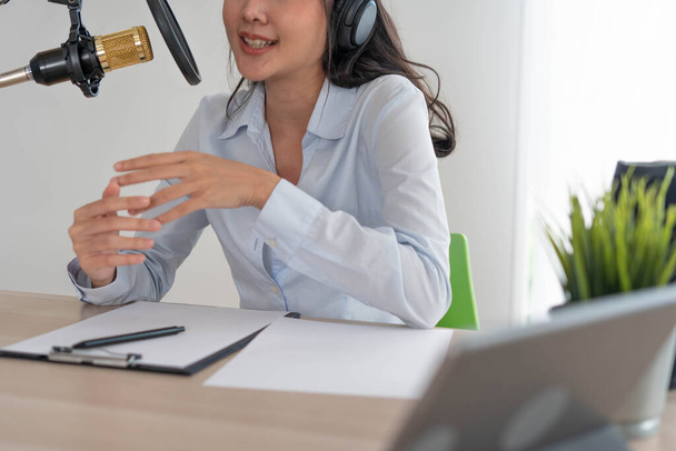 Bright Asian women record a podcast with a microphone and computer camera. A young woman work from home studio. broadcast studio concept - 写真・画像