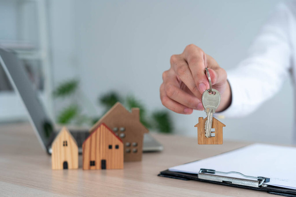Der Makler oder Immobilienmakler schickt das Schlüsselhaus nach Abschluss des Bauvorhabens an den Kunden. Kauf, Verkauf oder Hypothek Eigenheim für Darlehensgenehmigung. Wohngebäudeversicherung - Foto, Bild