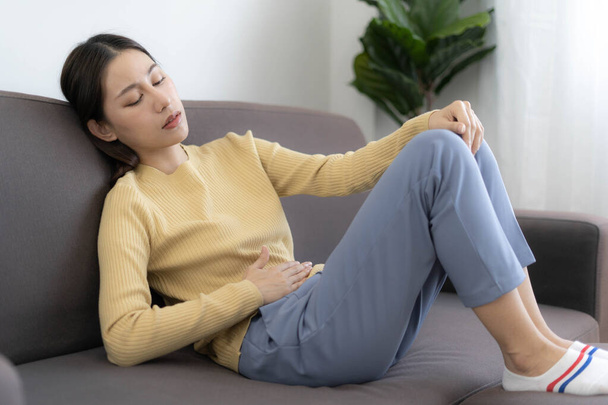 Asian women touch stomach, have stomachache, food allergies or menstrual cramps or Abdominal pain from colon cancer. sick at home - Photo, Image