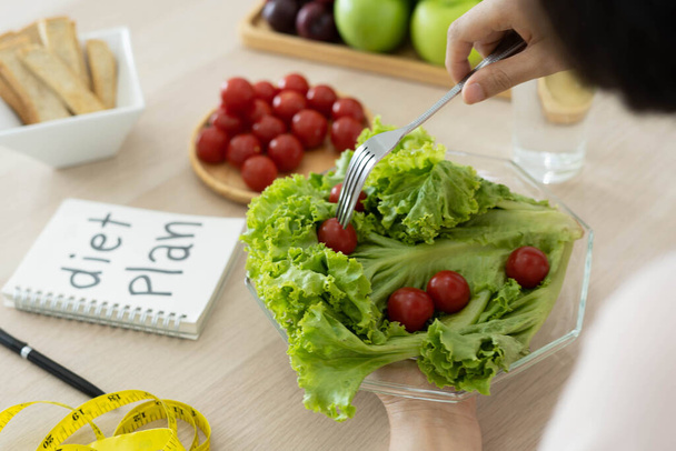 Comida saludable. Las mujeres planean la dieta para la forma delgada y saludable. Mujer comiendo verduras, ensaladas y tomates - Foto, imagen