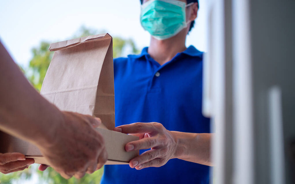 One woman ordered food online to eat at home. The person  orders products or food online, receives parcels from delivery man That put a mask on the door of the house. - Photo, image