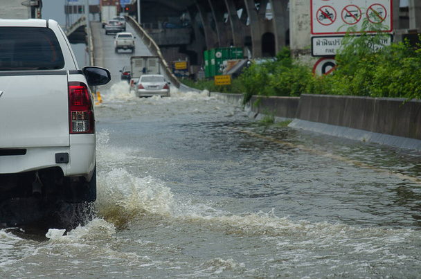 Rankkasade tulvii Thaimaan teitä. Auto kulkee tulvivan veden läpi.. - Valokuva, kuva