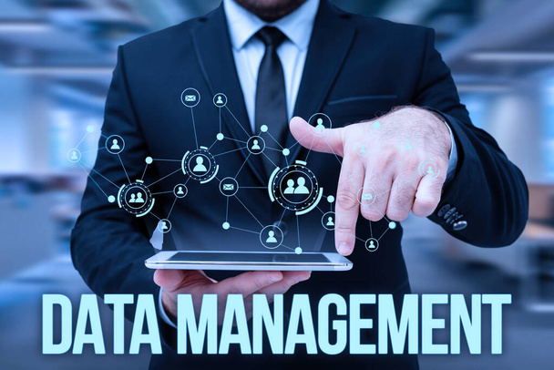 Conceptual caption Data Management. Word for The practice of organizing and maintaining data processes Man In Uniform Standing Holding Tablet Typing Futuristic Technologies. - Photo, Image