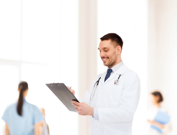 smiling male doctor with clipboard and stethoscope - 写真・画像