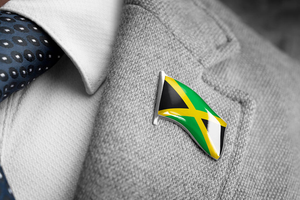 Μεταλλικό σήμα με τη σημαία της Τζαμάικα σε πέτο κοστούμι - Φωτογραφία, εικόνα