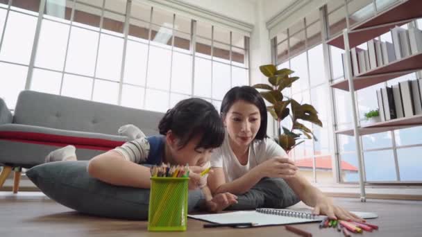 Mutter hilft ihrem Kind bei Malbuch-Hausaufgaben auf dem Fußboden für Haus und Online-Bildungskonzept. - Filmmaterial, Video