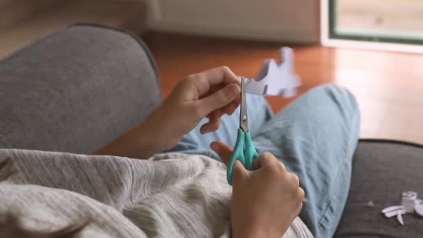 young child girl cutting out a snowflake from white paper with scissors at home, early education, crafting and art concept - Footage, Video