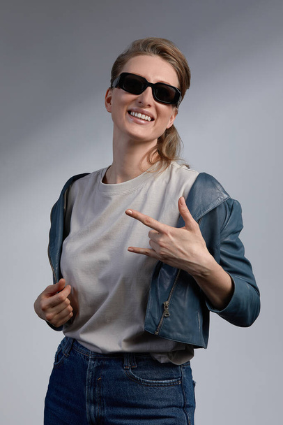 hullu nainen aurinkolasit osoittaa kielen rock ele merkkejä positiivisia tunteita. - Valokuva, kuva