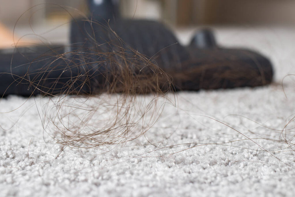 Kępa długich włosów na dywanie i zbliżenie odkurzacza. - Zdjęcie, obraz