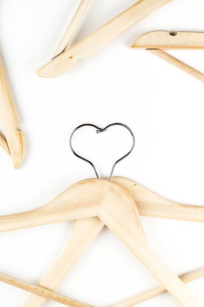 Conscious consumption slow fashion concept. Heart of clothes hangers entwined on white background.  - Photo, Image