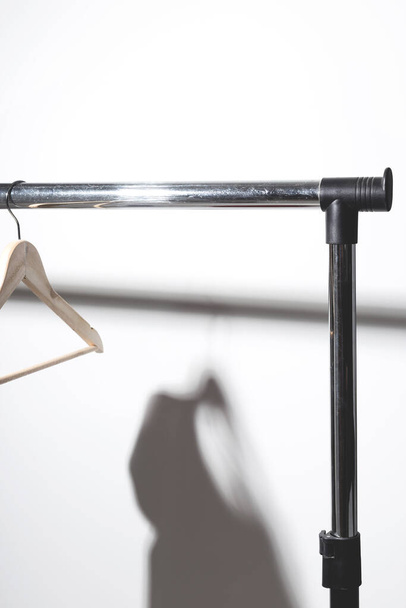 Leere Kleiderbügel auf einer Ebene mit Schatten von einem T-Shirt. Reinigung, Dekluttering und Minimalismus Konzeptkunst. - Foto, Bild