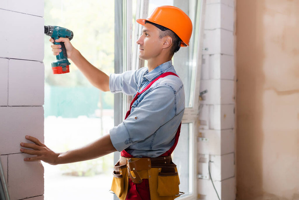trabajador constructor industrial masculino en la instalación de ventanas en el sitio de construcción de edificios - Foto, Imagen