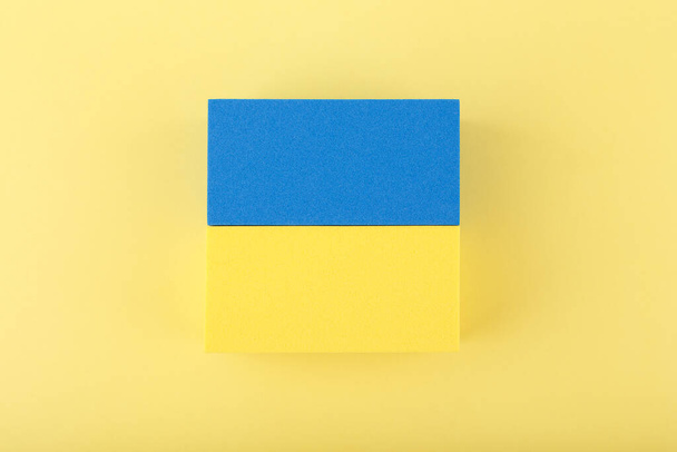 Creative flat lay with national flag of Ukraine made of toy rectangles on bright yellow background. Close up, horizontal, no people. - Photo, Image