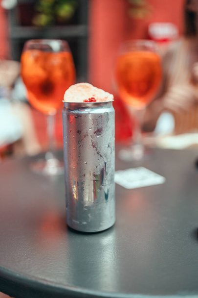 Καλοκαίρι κρύο αλουμίνιο μπορεί με αλκοολούχο ποτό και διακόσμηση στο τραπέζι και ελαφρύ bokeh σε μια υπαίθρια παμπ - Φωτογραφία, εικόνα