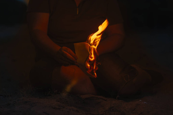 Une femme tient un bout de papier brûlant dans sa main. Une femme adulte - Photo, image