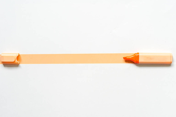 Ένα highlighter σε πορτοκαλί με ανοιχτό καπάκι. Σε πορτοκαλί και άσπρο χαρτί - Φωτογραφία, εικόνα