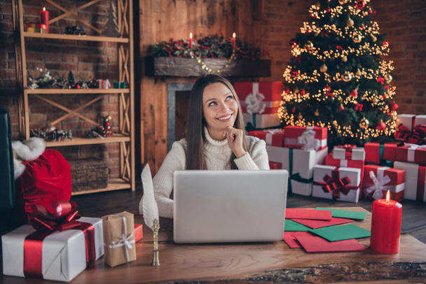 Portrait of attractive dreamy cheerful girl using laptop mail gift service at decorated room loft industrial interior home indoors - Фото, изображение