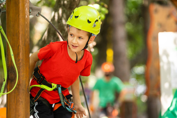 Cute school boy enjoying a sunny day in a climbing adventure activity park - Foto, Imagen