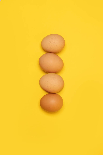 Syrová velikonoční kuřecí vejce na žlutém pozadí. Přírodní zdravé organické potraviny. Horní pohled, plochá poloha, kopírovací prostor. - Fotografie, Obrázek