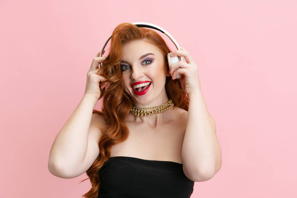 Ausgeschnittenes Porträt einer jungen effektiven Frau mit Kopfhörern auf rosa Hintergrund - Foto, Bild
