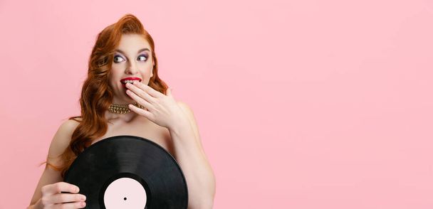 Portrait of beautiful excited Caucasian woman, singer holding vinyl record isolated over pink background. Flyer - Valokuva, kuva