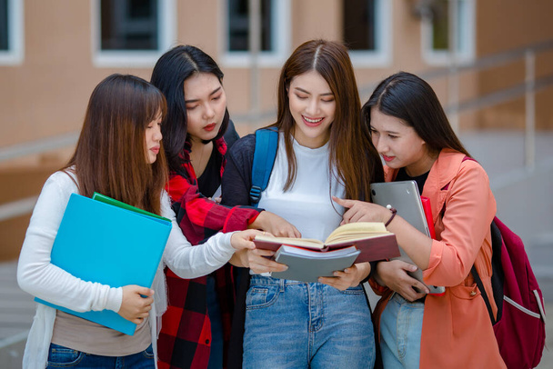 Üniversite kampüsünde notları olan neşeli Asyalı kız öğrencilerin arkadaşlığı eğlenceli ve samimi duygularla bir araya geliyor. Üniversite konseptinde yakın arkadaş. - Fotoğraf, Görsel