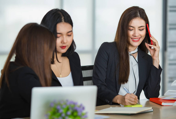 Empresa de mulheres empresárias asiáticas em roupas elegantes sentado tpgether à mesa no local de trabalho e discutir estratégia de negócios juntos enquanto olha para a câmera - Foto, Imagem