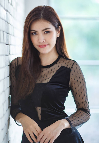 Retrato metade comprimento de conteúdo bonito encantador morena asiática feminina, Lao etnia, em elegante vestido preto de pé e posar com amigável positivo e auto-confiante pose. - Foto, Imagem