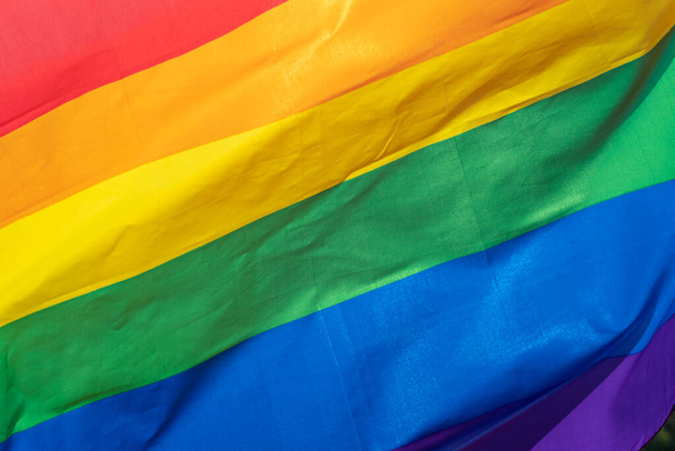 Rainbow flag (LGBT movement) on the sunny blue sky background. Colorful gay flag waving. - Fotó, kép