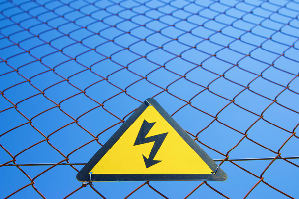 Σήμανση ηλεκτρικού κινδύνου τοποθετημένη σε μεταλλικό φράκτη. - Φωτογραφία, εικόνα
