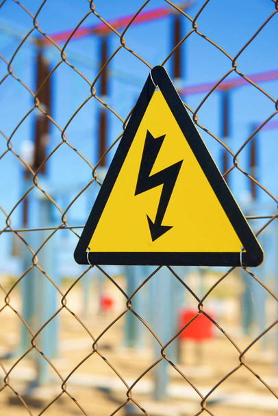 金属製の柵の上に設置された電気的危険標識. - 写真・画像
