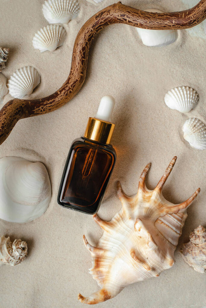 Essence for the health of facial skin. Mockup for your product. The collagen hydrating serum lies on the sand. Facial essence lies on the beach with seashells - Fotoğraf, Görsel