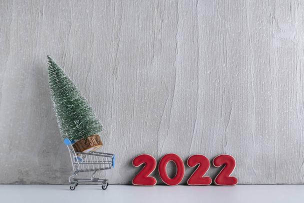 Miniature Christmas tree in trolley cart against the background of inscription 2022. Purchase and rent of Christmas trees. - Foto, Bild