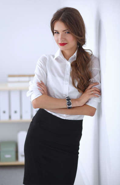 Attractive businesswoman with her arms crossed  standing in off - Foto, afbeelding
