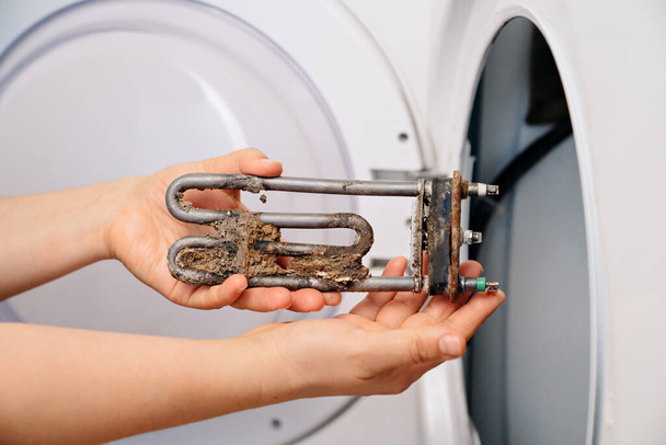 repair of washing machine. in hand old tubular electric heater - Zdjęcie, obraz