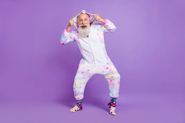 Full body photo of happy cool old man wear nightwear hands hood enjoy isolated on purple color background - Foto, immagini