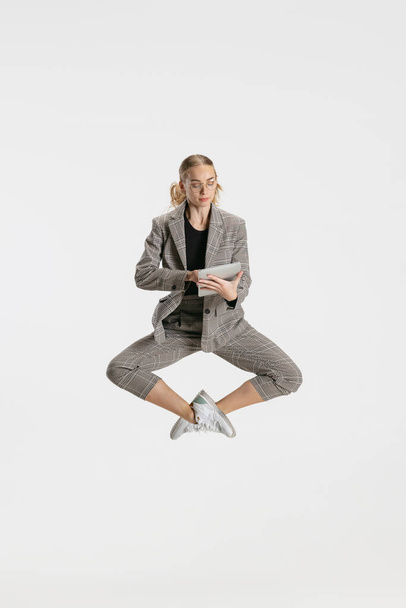 女性でカジュアルなオフィススタイルの服作りノートでザ · ジャンプ孤立した上のホワイトスタジオ背景 - 写真・画像