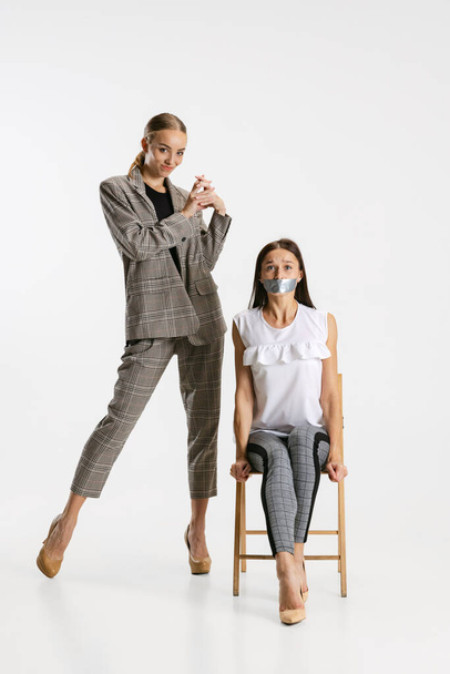 Funny image of two female workers isolated over white background. Tape your mouth - Fotografie, Obrázek